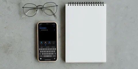 Reminders app on an iPhone next to a notepad  