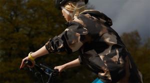 An Apple Watch user is shown riding a bicycle with Apple Watch on their wrist and iPhone mounted to the bike’s handlebars.