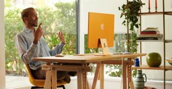 A man uses his new orange iMac, set up in his home office.  