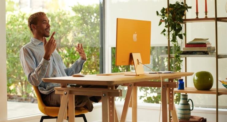 A man uses his new orange iMac, set up in his home office.  