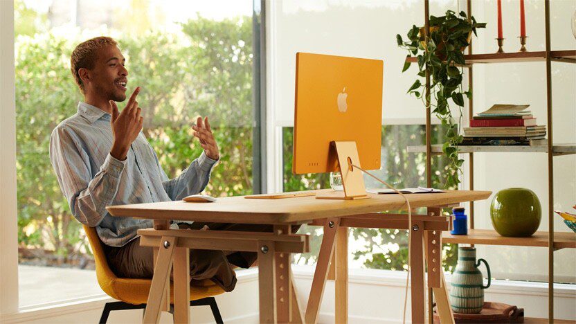 A man uses his new orange iMac, set up in his home office.  